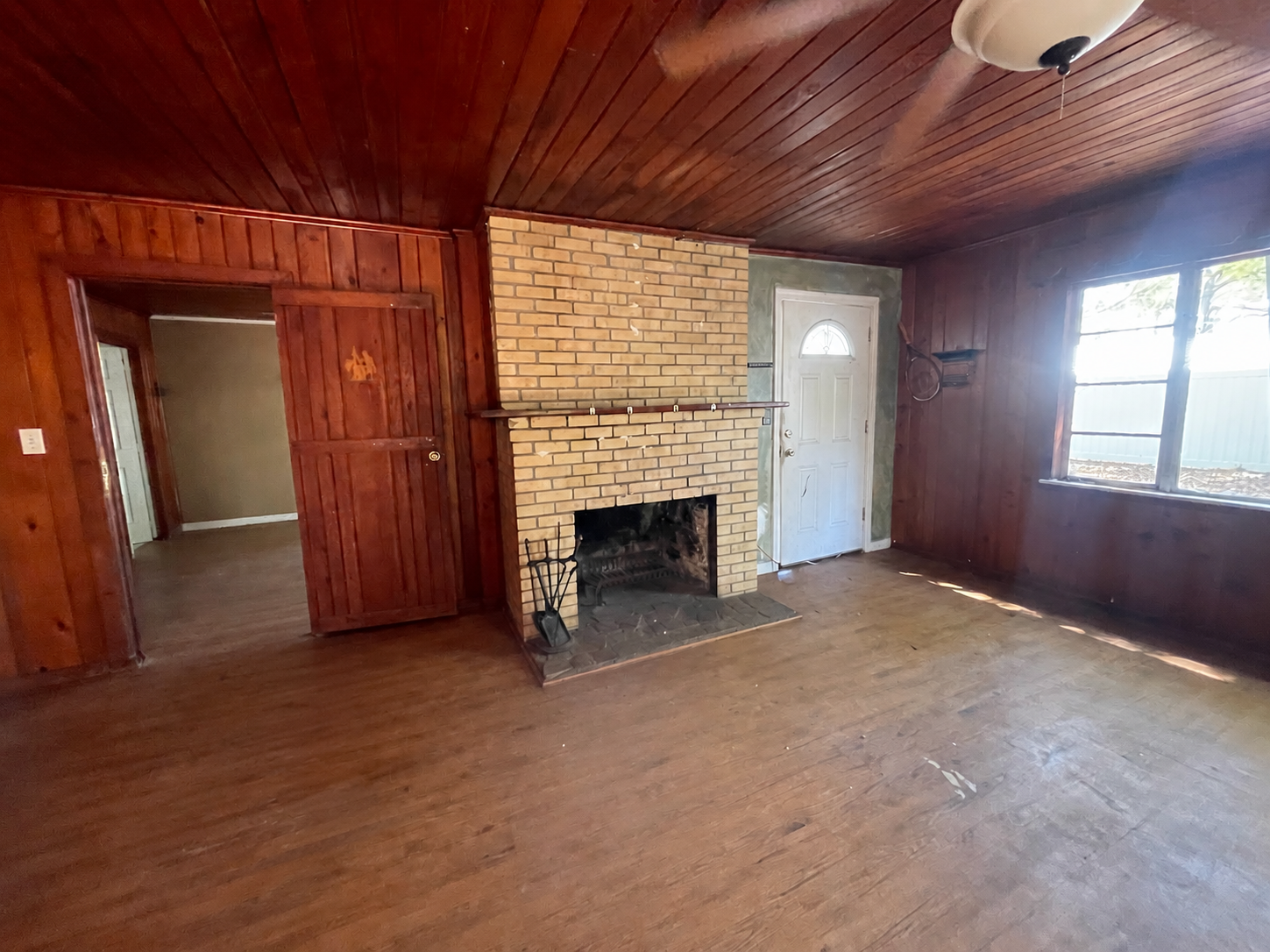Living room before renovation — original brick fireplace and wood paneling